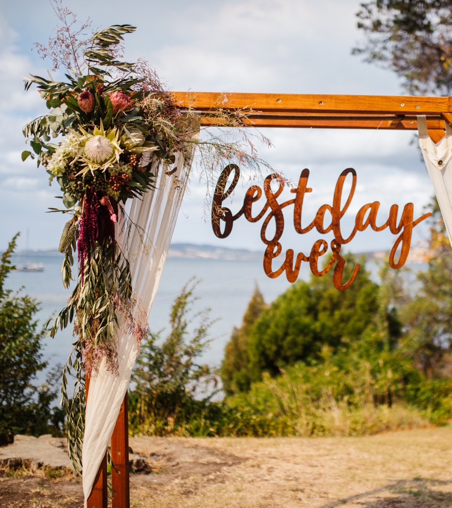 A wedding ceremony archway with floral installation and ocean views.